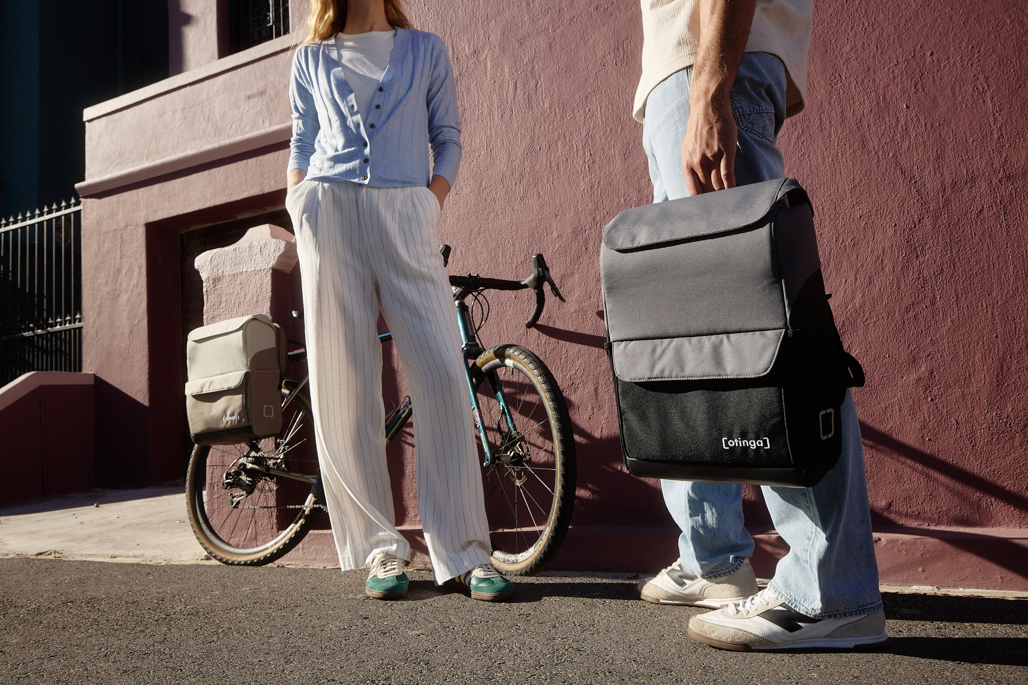 Zwei Personen mit Fahrradtaschen von otinga. Eine Tasche ist an einem Fahrrad montiert und eine andere Tasche wird von einer Person getragen.